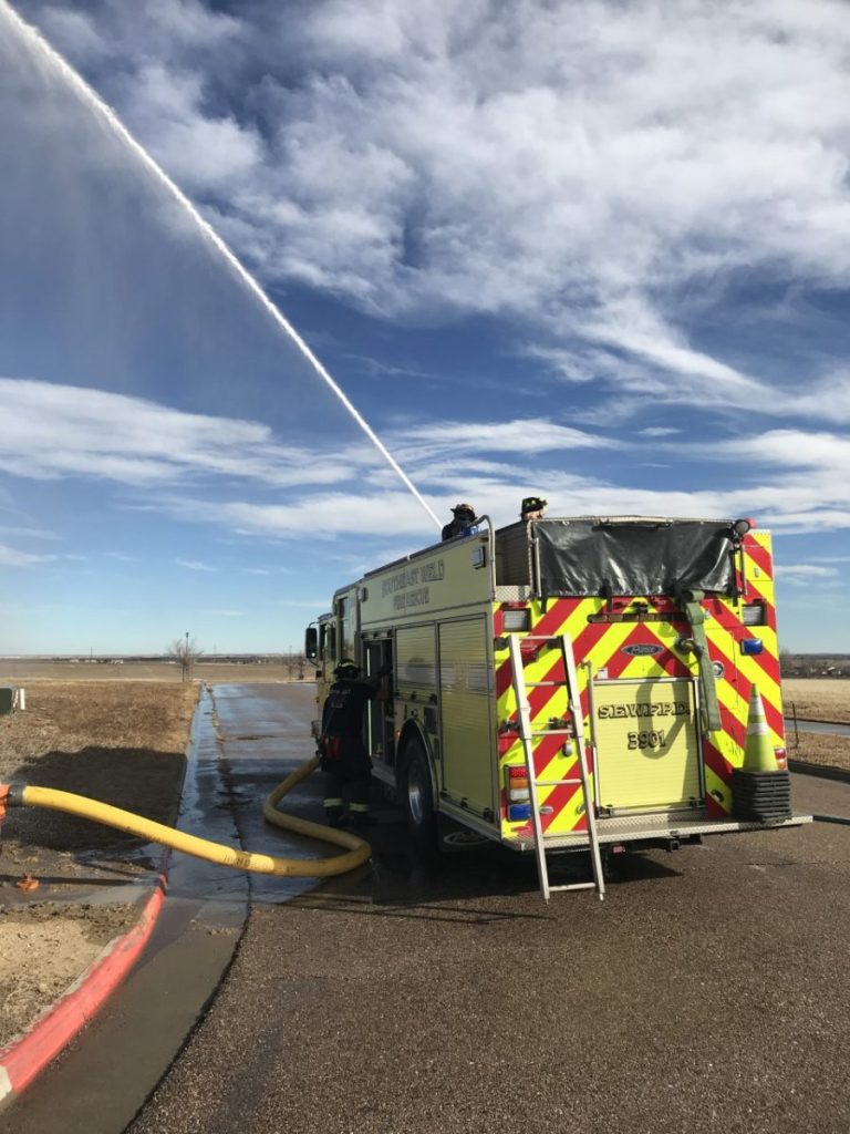 Fire engine with water shooting across the field